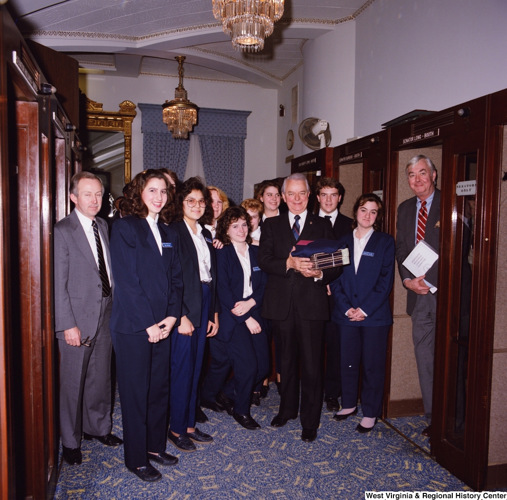 ["Senator Robert C. Byrd stands for a photograph with a group of Senate pages during his birthday celebration."]%