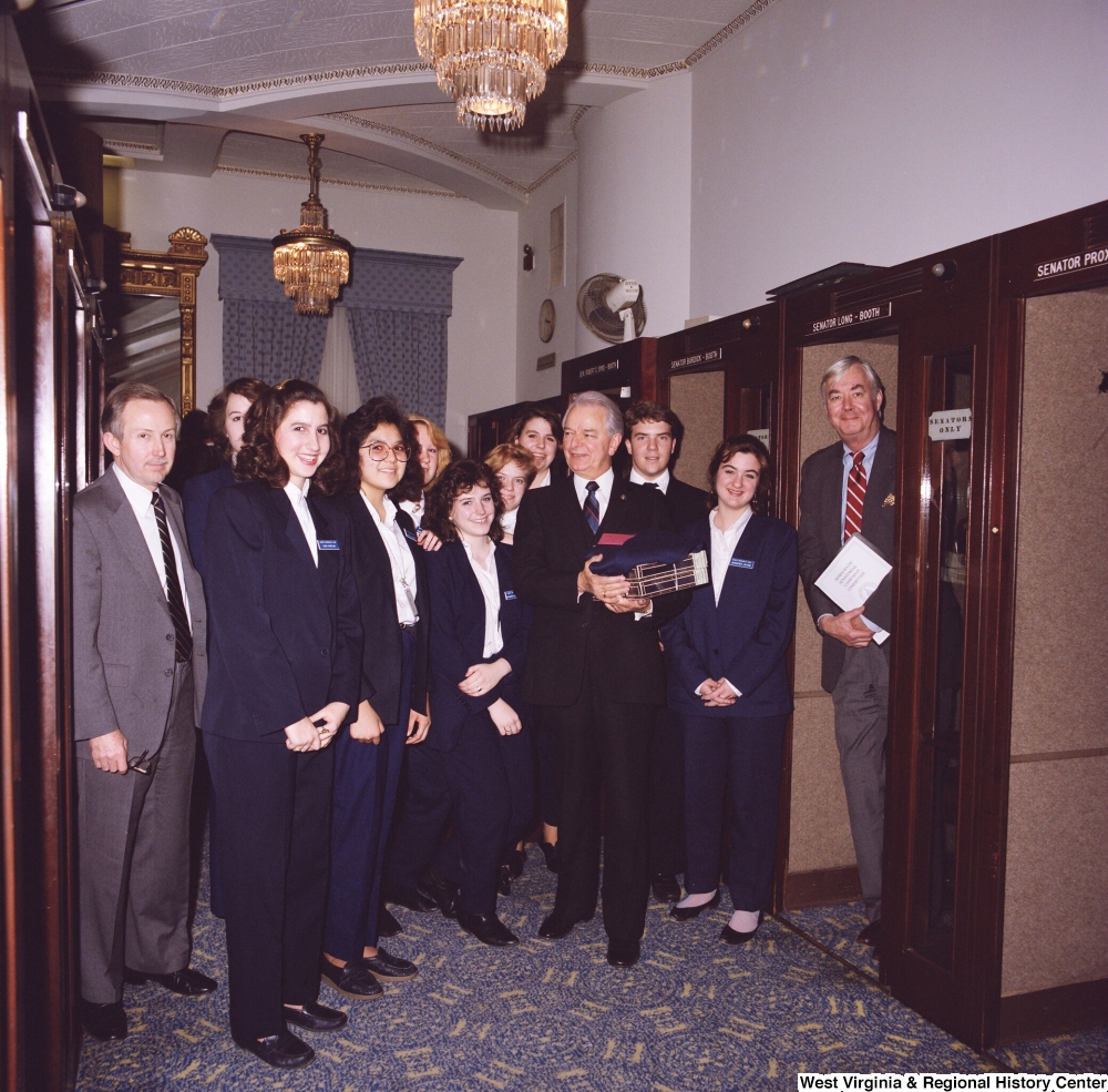 ["Senator Robert C. Byrd stands for a photograph with a group of Senate pages after his birthday celebration."]%
