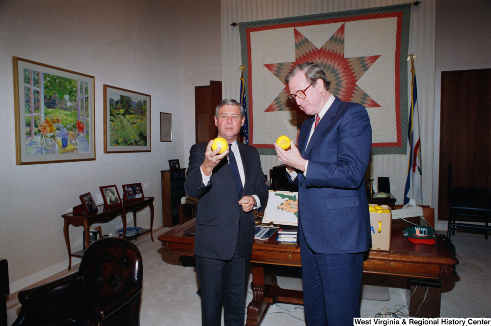 ["Senator John D. (Jay) Rockefeller inspects Florida oranges in his office with Senator Bob Graham."]%