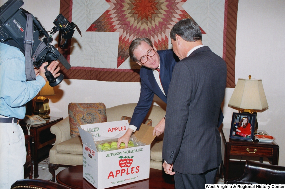 ["Senator John D. (Jay) Rockefeller shows Florida Senator Bob Graham a box of West Virginia apples."]%