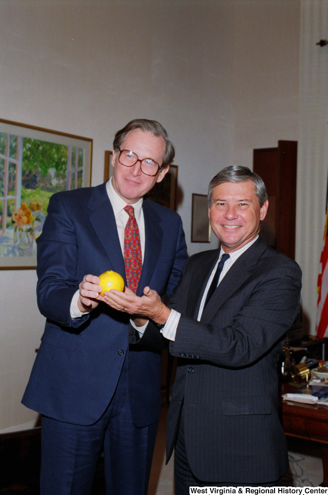 ["Senator John D. (Jay) Rockefeller and Senator Bob Graham pose for a photograph with a Florida orange."]%
